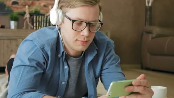 Ung skrattar man titta på strömmande film på smartphone äta spannmål med hörlurar — Stockvideo