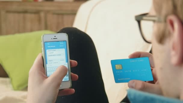 Young man filling credit card number on his smartphone paying for online shopping — Stock Video