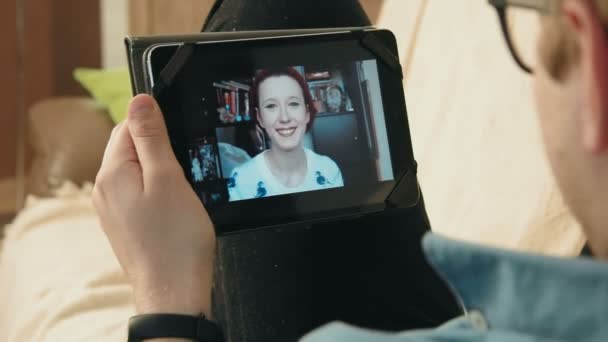Jeune homme ayant une conversation de chat vidéo sur sa tablette numérique avec une jeune femme hipster — Video
