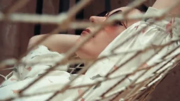 在她的公寓里的吊床上戴眼镜放松的短发女人 — 图库视频影像