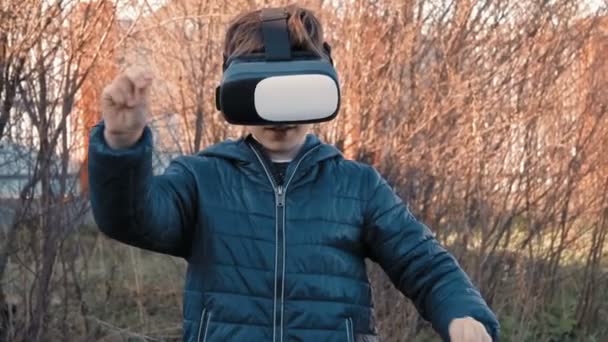 Niño utiliza auriculares de realidad virtual al aire libre — Vídeos de Stock