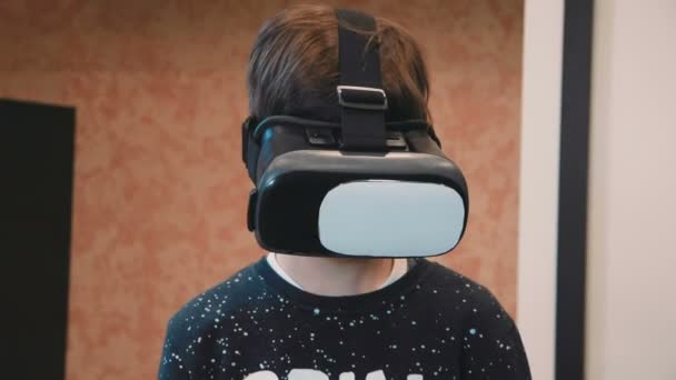 Πορτρέτο του ένα μικρό αγόρι που φοράει σετ κεφαλής εικονικής πραγματικότητας και χαμογελαστός — Αρχείο Βίντεο
