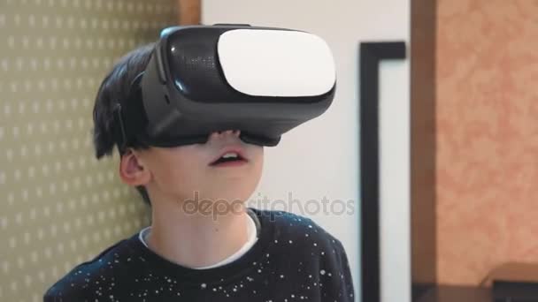 Маленький мальчик удивлен опытом виртуальной реальности с помощью гарнитуры — стоковое видео