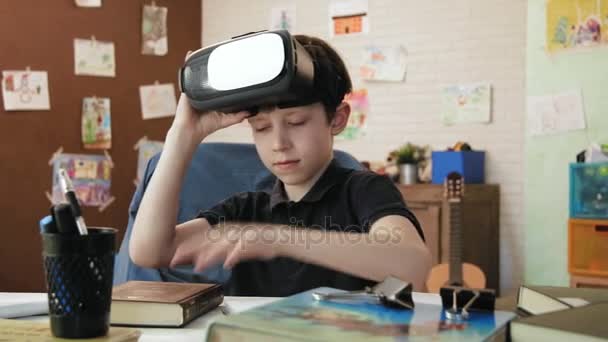 Menino bonito lendo um livro e colocar em fone de ouvido realidade virtual e parece surpreso em seu quarto — Vídeo de Stock