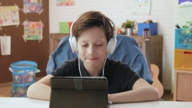 Kulaklıklar giyen sevimli küçük çocuk komik video dijital tablet kullanarak izleme