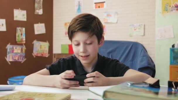 Schattige kleine jongen spelen van computerspel op smartphone — Stockvideo