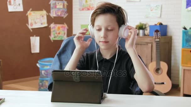 Lindo niño escuchando música en su tableta digital con auriculares — Vídeo de stock