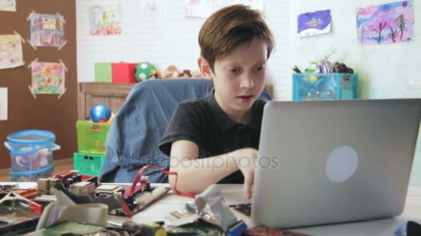 Lindo niño codificación de nuevos componentes de la computadora usando su tipo de ordenador portátil en el teclado — Vídeos de Stock