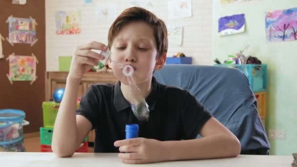 Leuke jongen bellen blazen in zijn kamer — Stockvideo