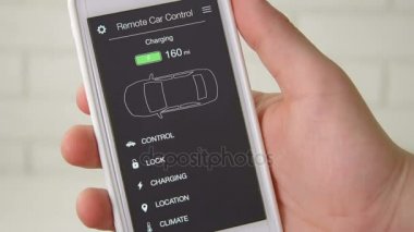 Adam onun elektrikli araba şarj düzeyini denetler. Pil doludur. Araba uzaktan kumanda smartphone uygulama kurgusal arabirimini kullanarak.