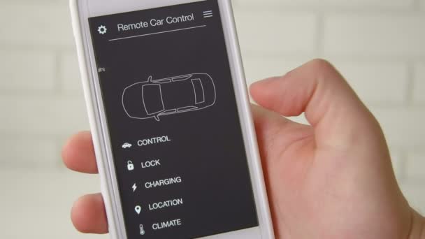 Homem muda remotamente a temperatura em seu carro Controle remoto do carro usando a interface fictícia do aplicativo do smartphone . — Vídeo de Stock