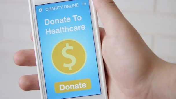 Mann spendet online für Healthcare mit Charity-Applikation auf Smartphone — Stockvideo