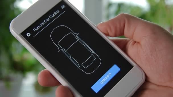 男は、モバイル デバイスで車の情報を確認します。良好な状態。スマート フォン アプリケーション架空インターフェイスを使用して車のリモコン. — ストック動画