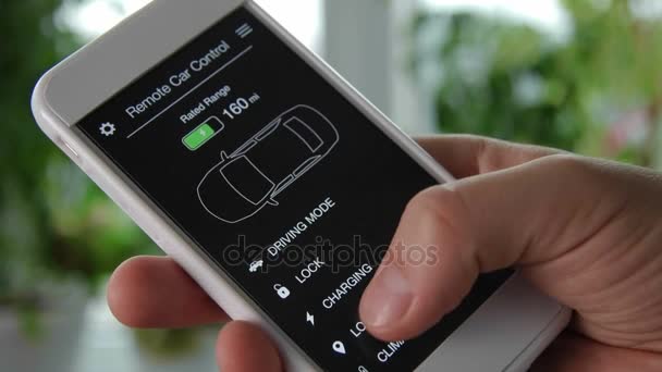 Adam araba yerini taşınabilir aygıt kullanarak denetler. Araba uzaktan kumanda smartphone uygulama kurgusal arabirimini kullanarak. — Stok video