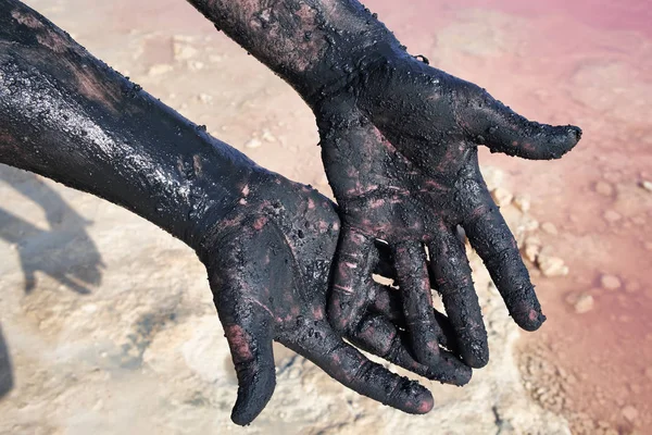 Hands of men smeared black mud. Close-up. At lake Las Salinas, Torrevieja. Spain. — Stock Photo, Image