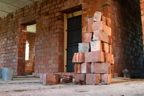 Pile of Bricks by an Old Brick Wall taken by an old building in St. Petersburg. Metal buckets on the construction site.