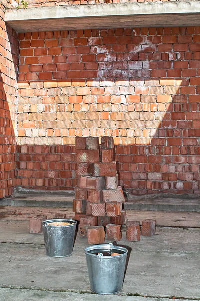 Pile of Bricks by an Old Brick Wall taken by an old building in St. Petersburg. Metal buckets on the construction site.