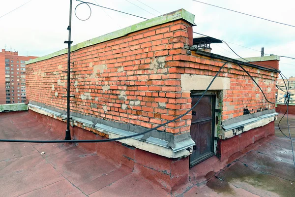 Vue sur les éléments du toit d'un bâtiment moderne en brique de plusieurs étages. La ventilation, la porte du grenier, l'ascenseur de la tour. Fils, câbles, imperméabilisation et drainage. Saint-Pétersbourg — Photo