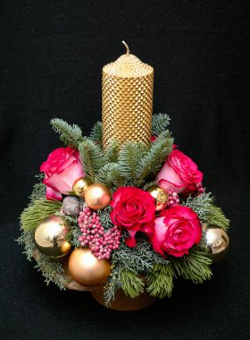 Noel kompozisyon bir mum Merkezi, Çamın dalları, ardıç, pembe Gül, pembe biber, koni ve altın top. Yeni yıl kompozisyon koyu arka plan üzerinde.