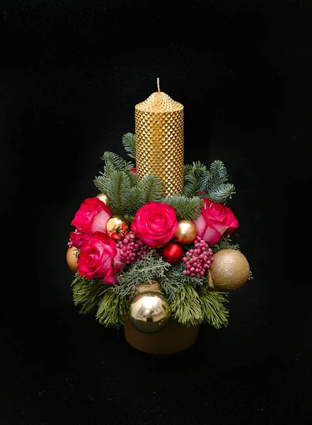 Christmas composition with a candle in the center, pine branches, juniper, pink roses, pink pepper, cones, and golden balls. New Year composition on a dark background. — Stock Photo, Image