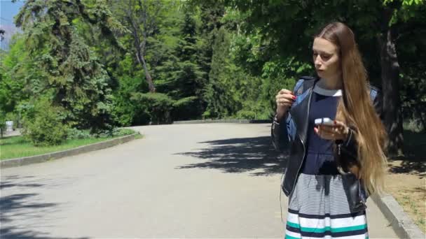 Привлекательная молодая девушка со смартфоном, на открытом воздухе — стоковое видео