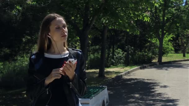 スマート フォンで、屋外の魅力的な若い女の子 — ストック動画