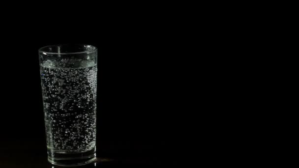 Eau minérale fraîche dans un verre sur fond noir — Video