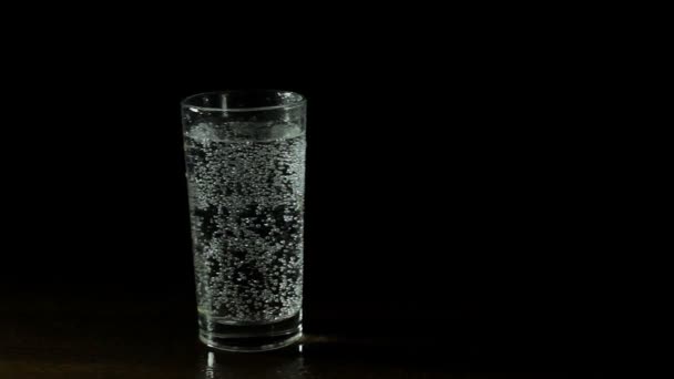 Свежая минеральная вода в стакане на черном фоне — стоковое видео