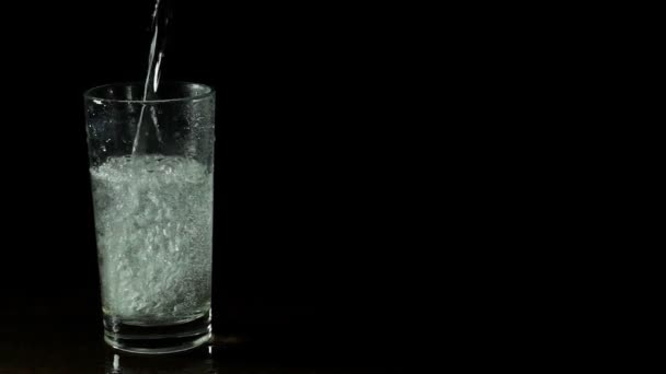 Água mineral fresca em um copo no fundo preto — Vídeo de Stock