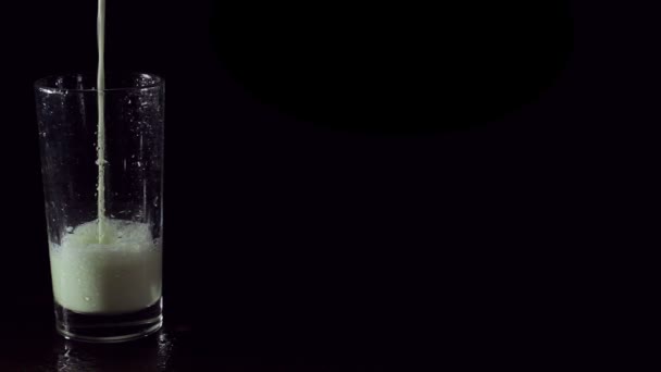 Leckere und gesunde Milch in einem Glas auf schwarzem Hintergrund — Stockvideo