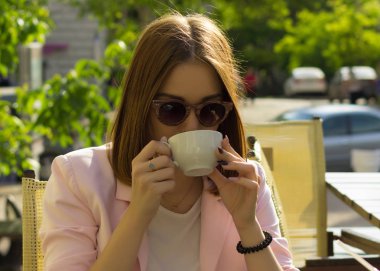 Genç güzel kız sıcak içecek, açık bir fincan içecekler