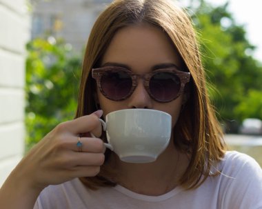 Genç güzel kız sıcak içecek, açık bir fincan içecekler