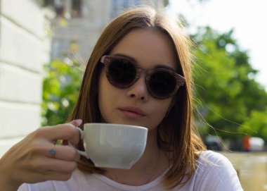 Genç güzel kız sıcak içecek, açık bir fincan içecekler