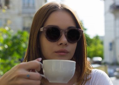 Genç güzel kız sıcak içecek, açık bir fincan içecekler