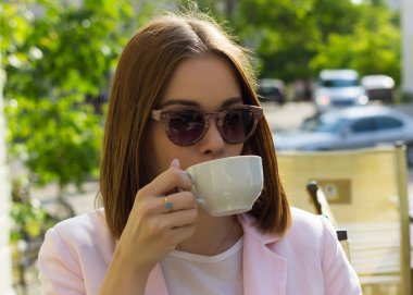 Genç güzel kız sıcak içecek, açık bir fincan içecekler