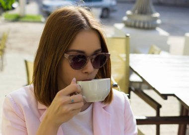 Genç güzel kız sıcak içecek, açık bir fincan içecekler