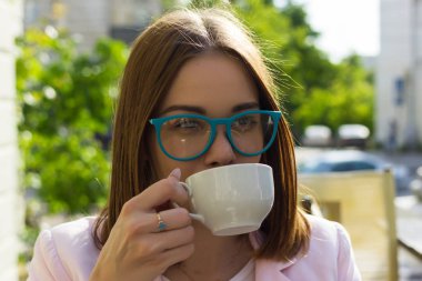 Genç güzel kız sıcak içecek, açık bir fincan içecekler