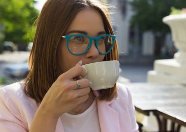 Genç güzel kız sıcak içecek, açık bir fincan içecekler