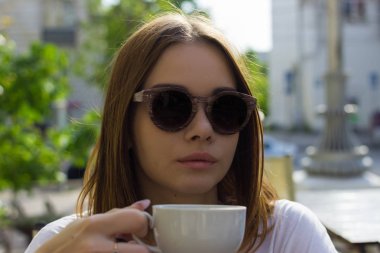 Genç güzel kız sıcak içecek, açık bir fincan içecekler