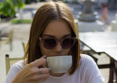 Genç güzel kız sıcak içecek, açık bir fincan içecekler