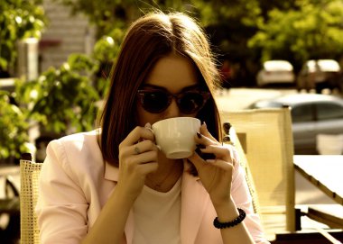 Genç güzel kız sıcak içecek, açık bir fincan içecekler