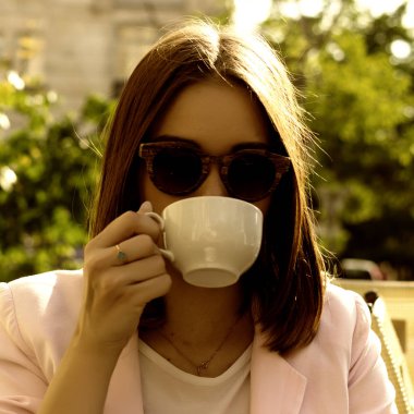 Genç güzel kız sıcak içecek, açık bir fincan içecekler