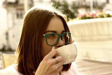 Genç güzel kız sıcak içecek, açık bir fincan içecekler