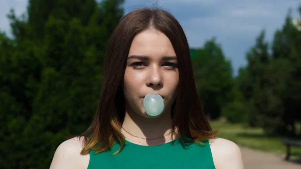 Jovem menina bonita mastiga uma gengiva, ao ar livre — Fotografia de Stock