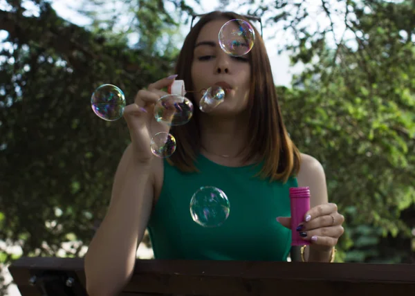 Joven chica bonita sopla burbujas, al aire libre —  Fotos de Stock