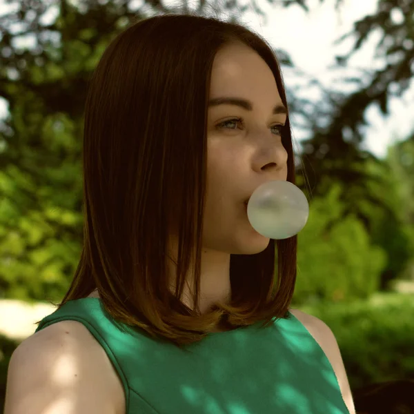 Joven chica bonita mastica un chicle, al aire libre — Foto de Stock