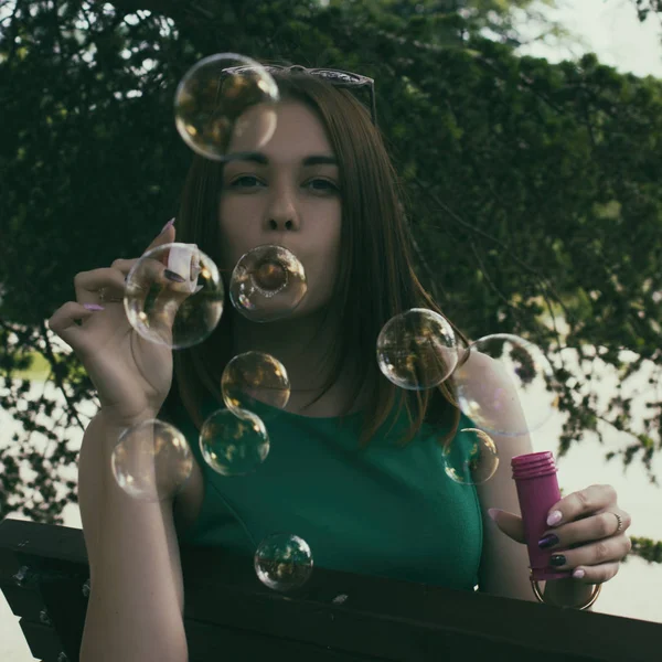Joven chica bonita sopla burbujas, al aire libre — Foto de Stock