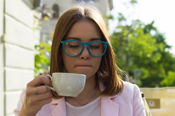 Genç güzel kız sıcak içecek, açık bir fincan içecekler