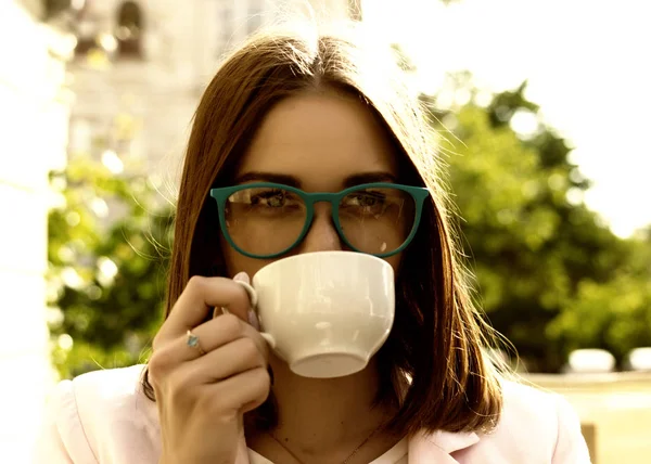 Jeune jolie fille boit une tasse de boisson chaude, en plein air — Photo