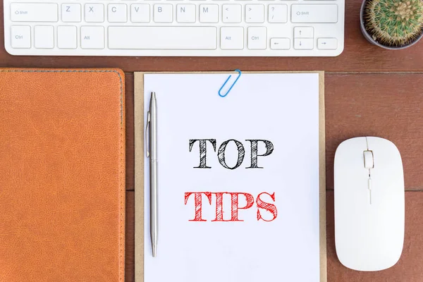 Text Top tips on white paper which has keyboard mouse pen and office equipment on wood background / business concept.